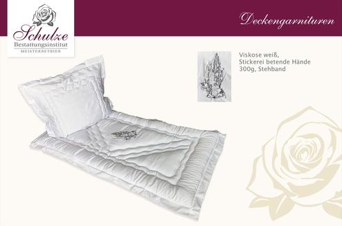 Weißes Bettwäsche-Set aus Viskose mit gesticktem Design und Stehband auf blassem Hintergrund.