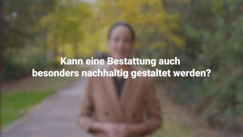 Frau im Park fragt, ob eine Bestattung nachhaltig gestaltet werden kann. Bäume und bunte Blätter im Hintergrund.