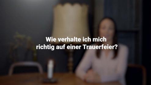 Eine Frau sitzt an einem Tisch mit einer Lampe und fragt, wie man sich richtig auf einer Trauerfeier verh&auml;lt.