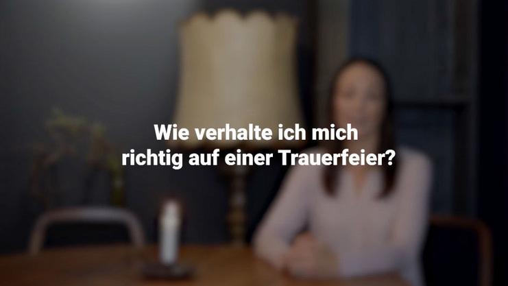 Eine Frau sitzt an einem Tisch mit einer Lampe und fragt, wie man sich richtig auf einer Trauerfeier verh&auml;lt.