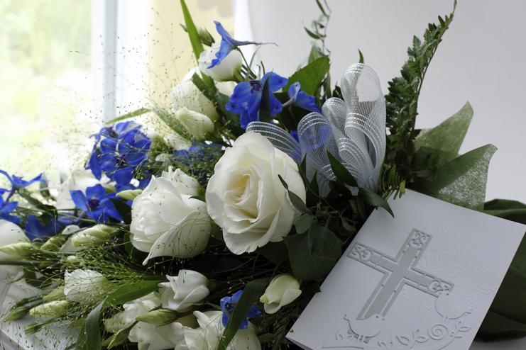 Blumenarrangement mit weißen Rosen und blauen Blüten, kombiniert mit einer tiefen Karte mit gekreuztem Motiv.