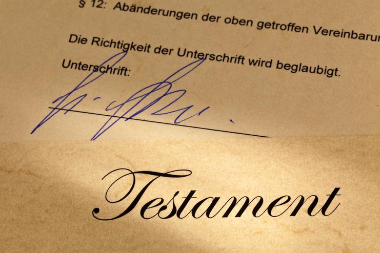 Nahaufnahme eines Dokuments mit der Überschrift "Testament" und einer handschriftlichen Unterschrift.